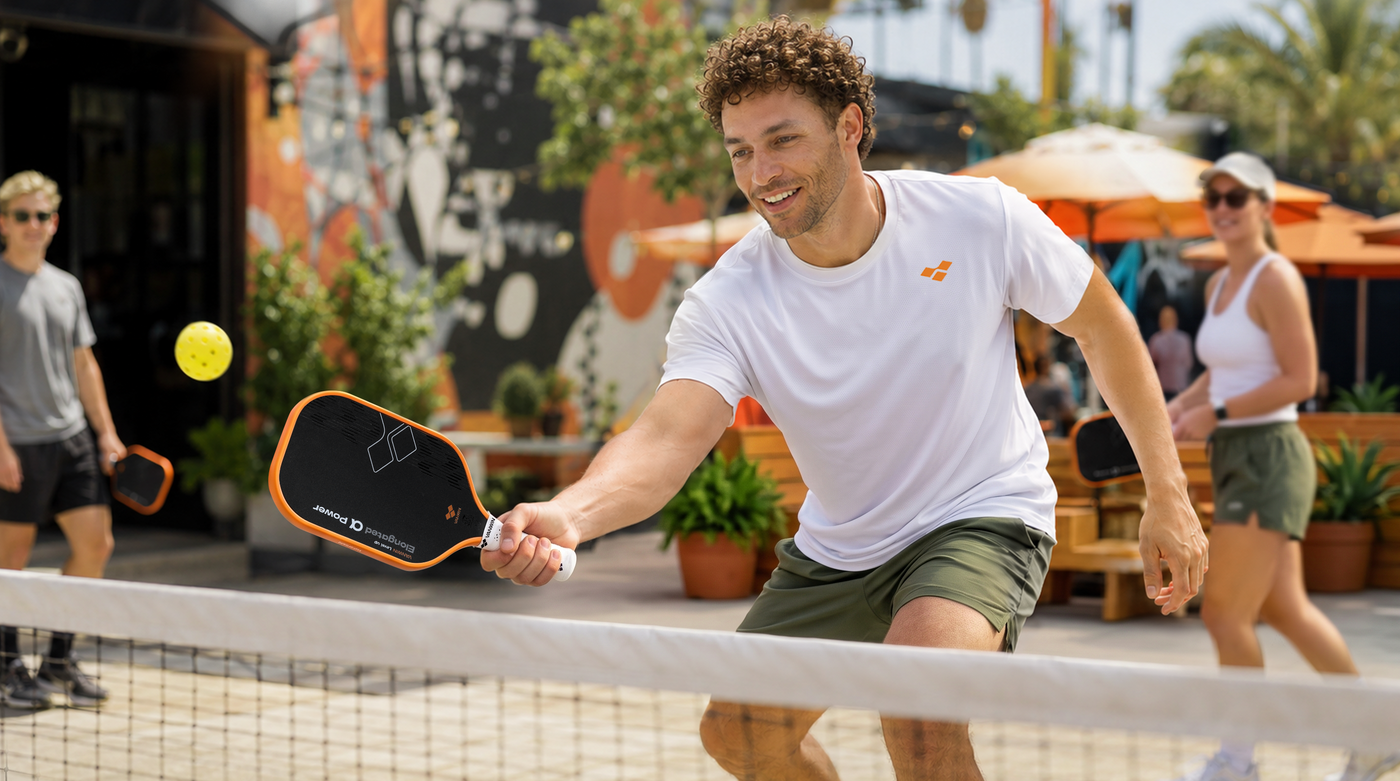 Player hitting a pickleball with a VANWIN Alpha Power paddle on an outdoor court